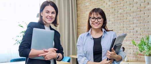 Two females smiling at camera in office corporate